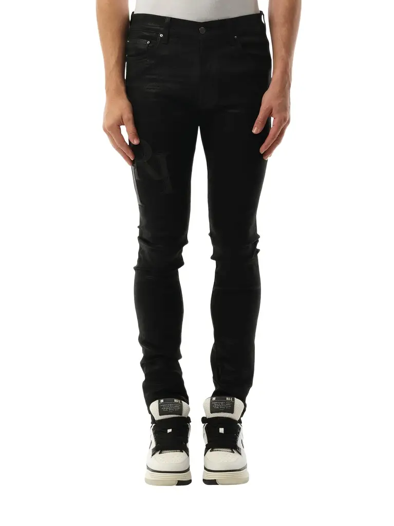 AMIRI Waxed Staggered Logo Skinny Jeans in Black Wax | Image 1 AMIRI Waxed Staggered Logo Skinny Jeans in Black Wax | Image 1